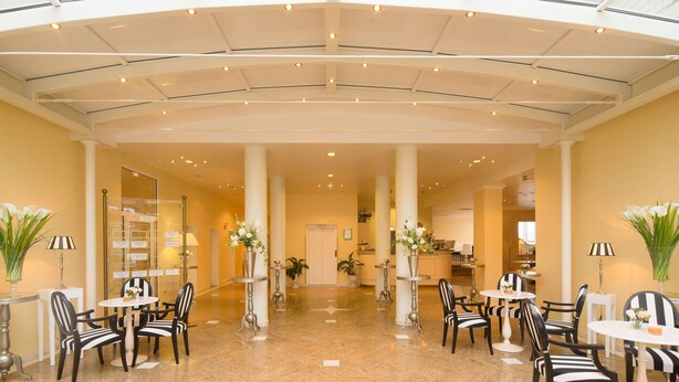 A spacious lobby with a high ceiling, multiple seating areas, and a glass atrium. - Trip Inn Hotel Astoria Göttingen (Goettingen)