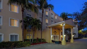 A hotel entrance with a covered area, palm trees, and a sign reading "Homewood Suites." - Homewood Suites by Hilton Bonita Springs Naples North (Bonita Springs)