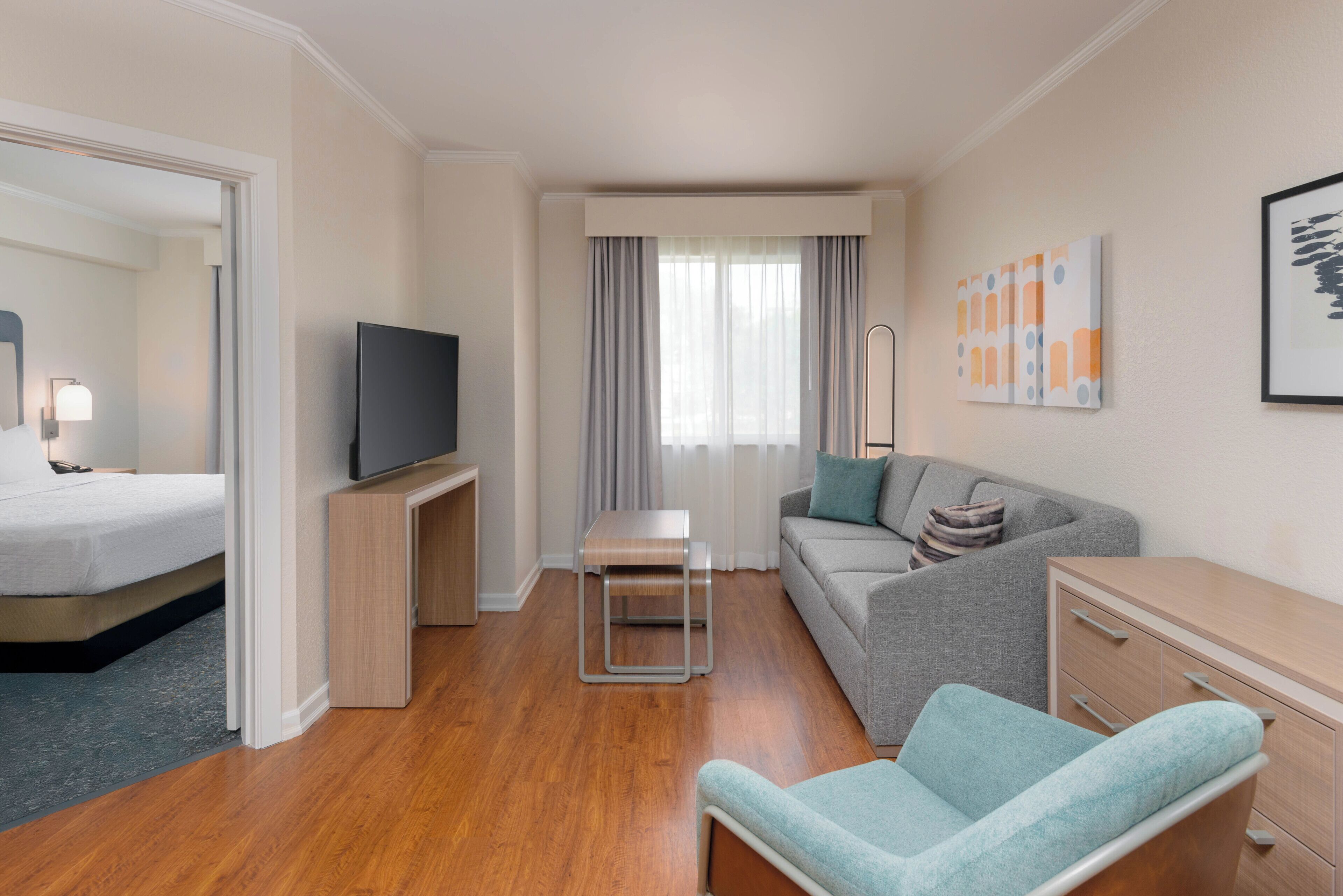 Ein Hotelzimmer mit Bett, Fernseher, Sofa, Schreibtisch und Stuhl.