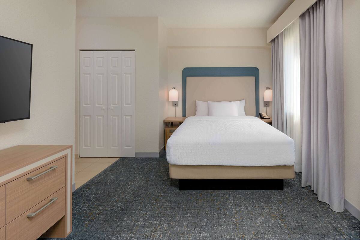 Ein Hotelzimmer mit einem Bett, einem Fernseher, einem Schreibtisch und einem Kleiderschrank.