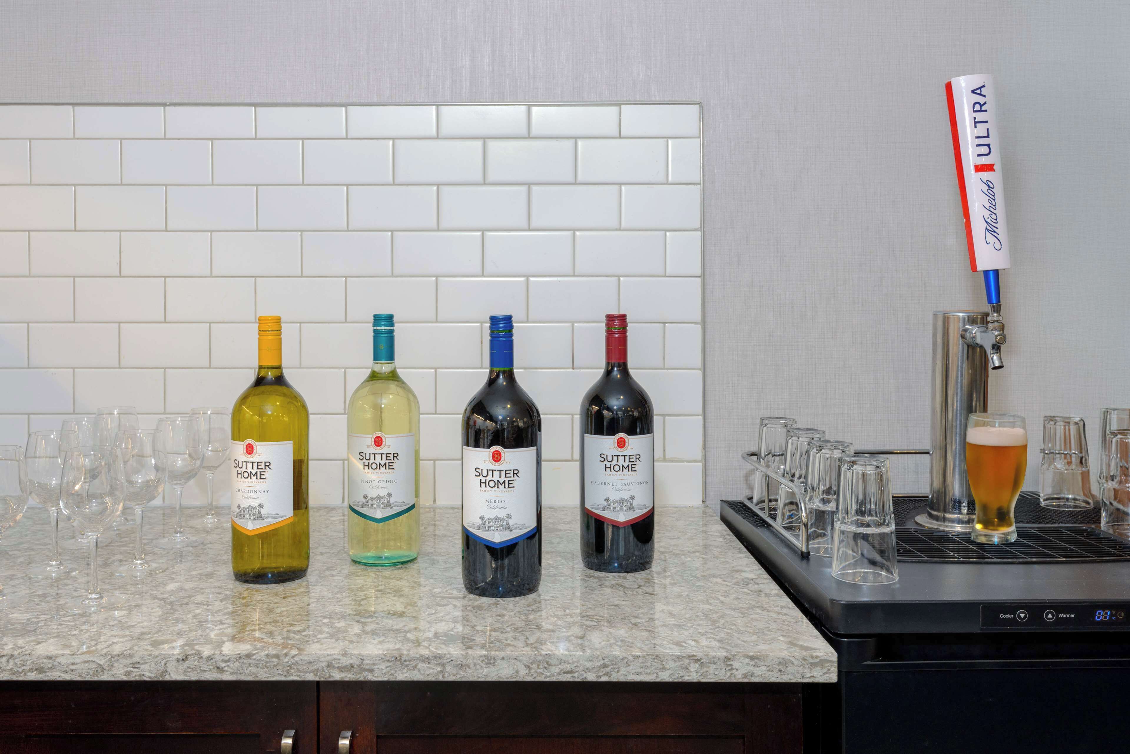 A bar area with four bottles of Sutter Home wine and a beer tap.