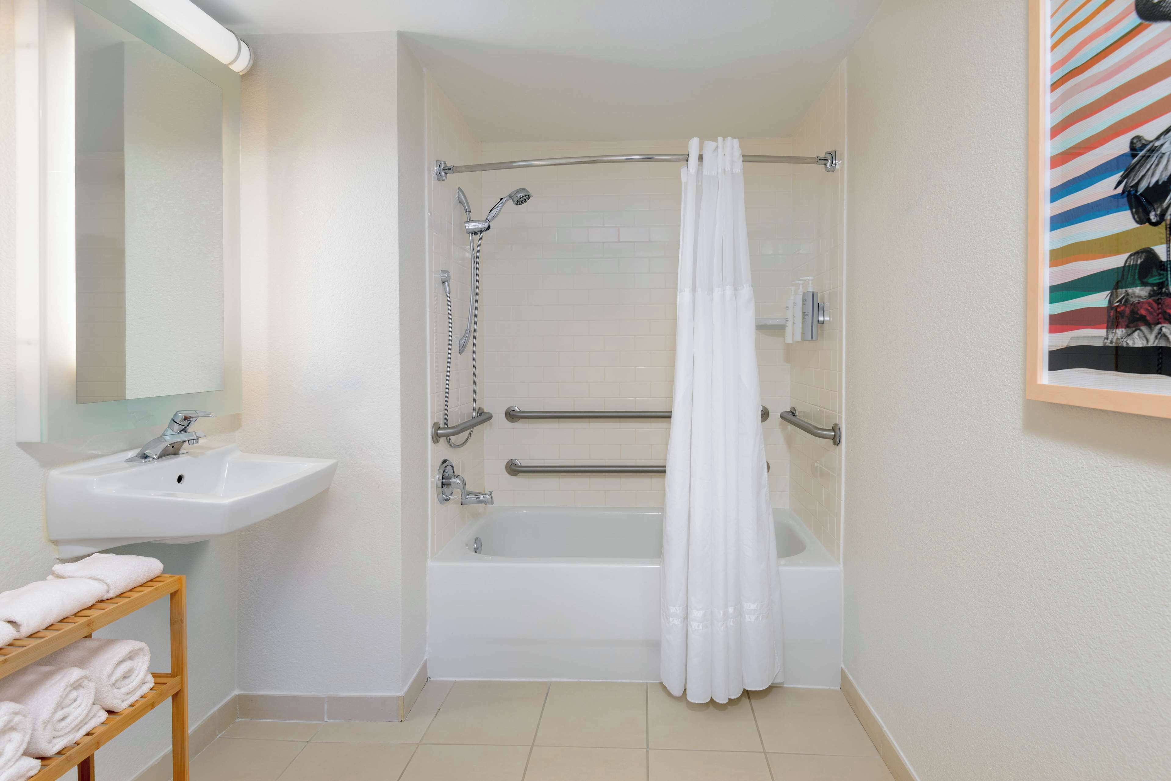 A bathroom with a sink, mirror, shower, and bathtub.