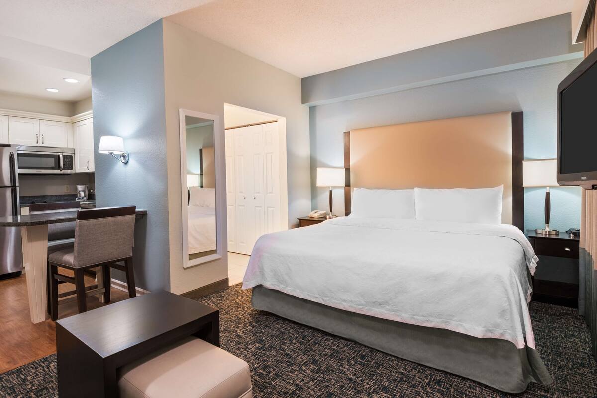 Ein Hotelzimmer mit Bett, Schreibtisch, Stuhl, Mikrowelle und Fernseher.