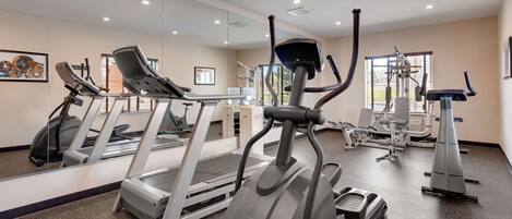 Un gimnasio moderno con cintas de correr, elípticas y equipo de pesas.