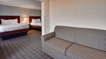 A hotel room with two beds, a sofa, and a patterned carpet.
