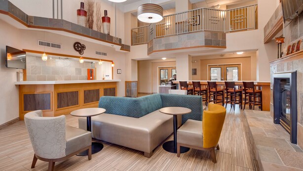 A spacious lobby with a central seating area, a bar, and a fireplace. - Best Western Plus Gateway Inn & Suites (Aurora)