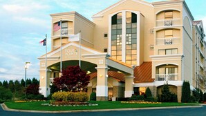 Un hotel con una entrada destacada, varios balcones y una bandera.