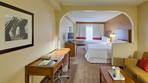 Una habitación de hotel con cama, escritorio, silla y televisor.