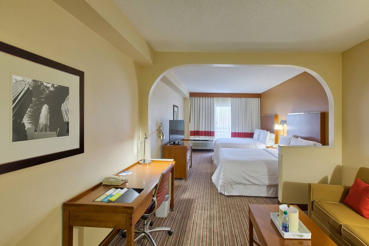Una habitación de hotel con cama, escritorio, silla y televisor.
