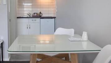 Cozinha compacta com micro-ondas, armários e mesa de vidro com cadeiras.