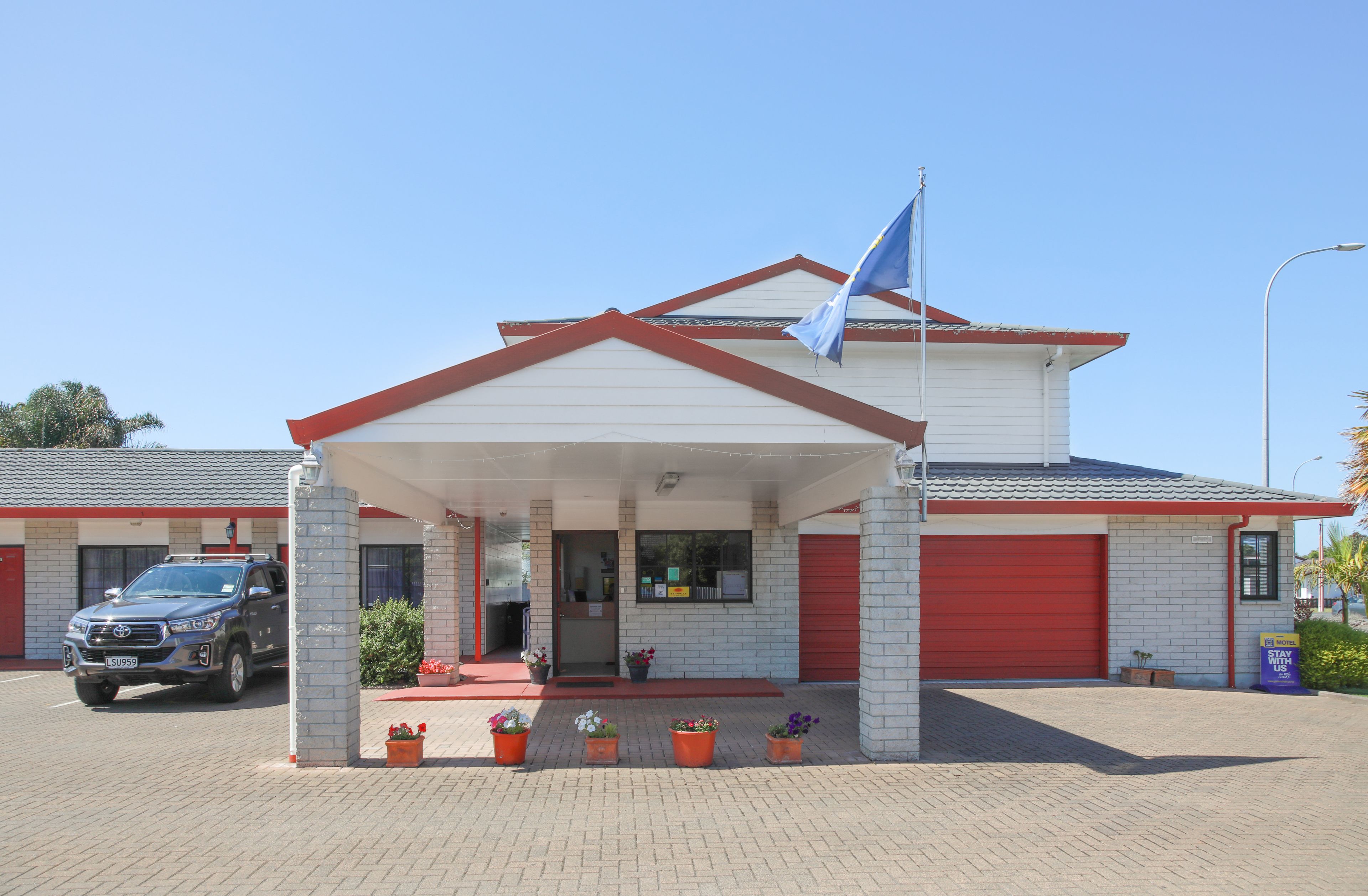 A building with a red garage door, a covered entrance, and a flag.
