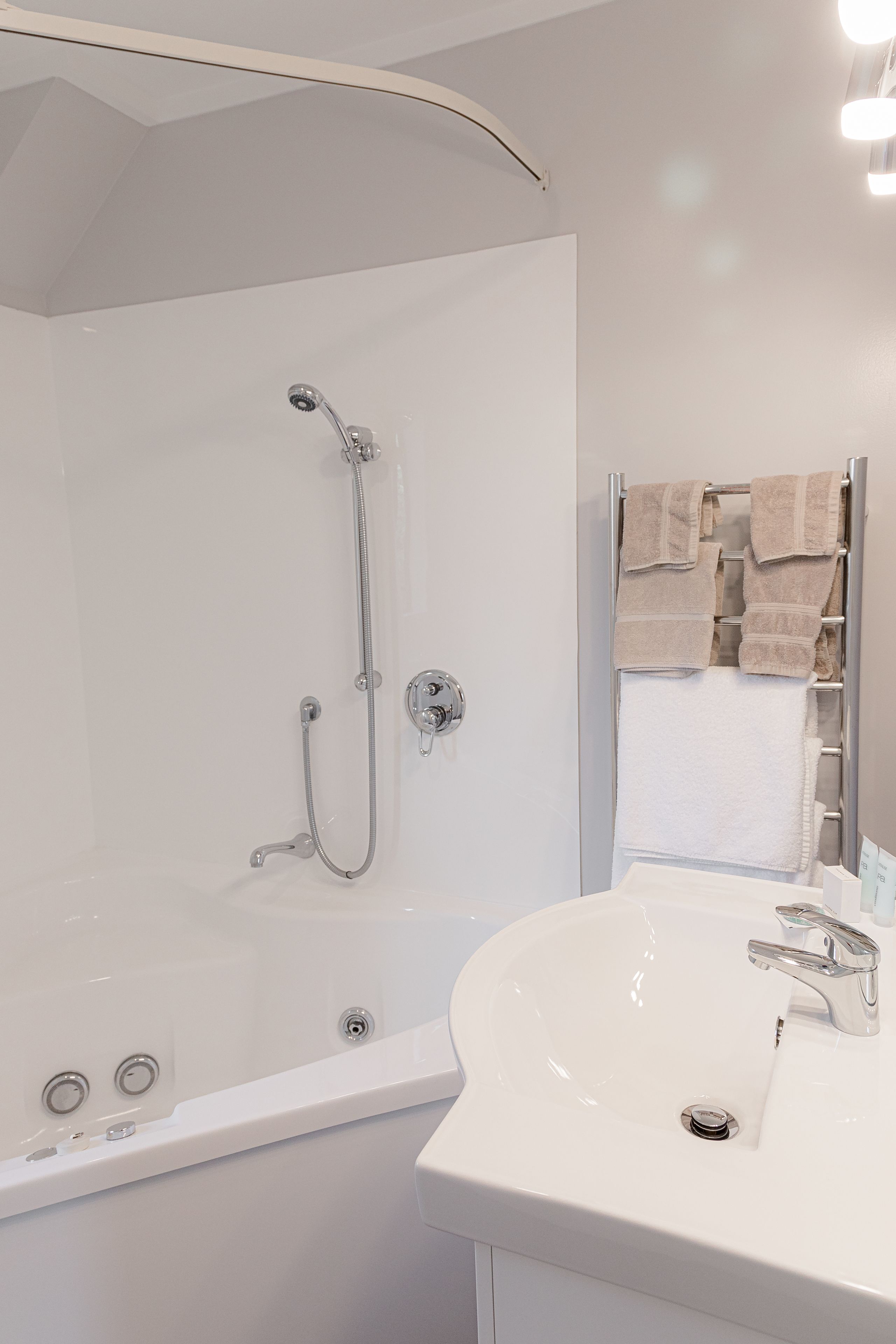 A modern bathroom with a walk-in shower, a white sink, and a towel rack.