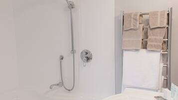 A modern bathroom with a walk-in shower, a white sink, and a towel rack.
