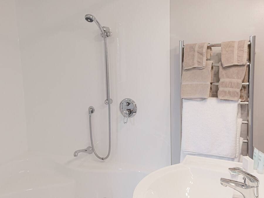 A modern bathroom with a walk-in shower, a white sink, and a towel rack.