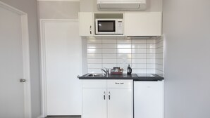 A modern kitchen with white cabinetry, a built-in microwave, and a dishwasher. - Bk's Palm Court Motor Lodge (Gisborne)