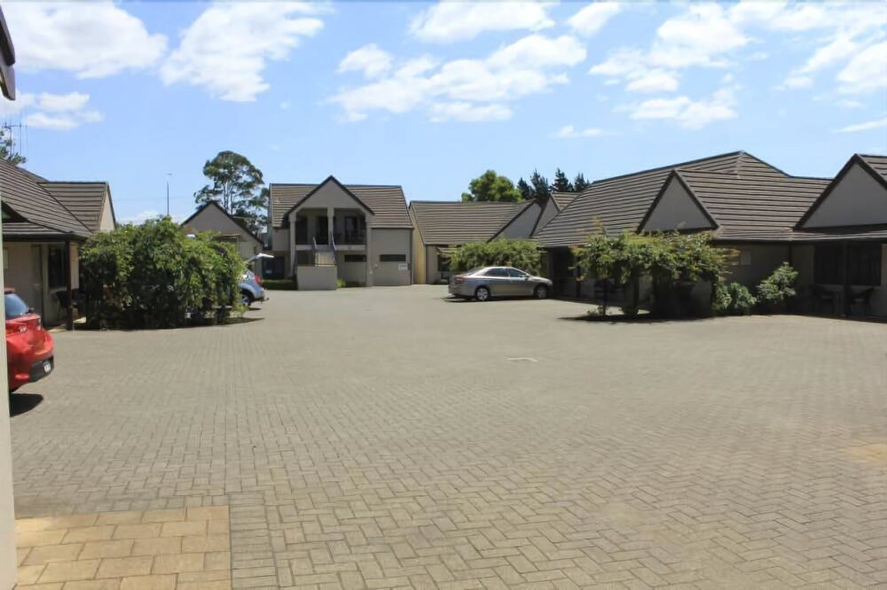 Zona residencial com casas, calçada pavimentada e carros estacionados.
