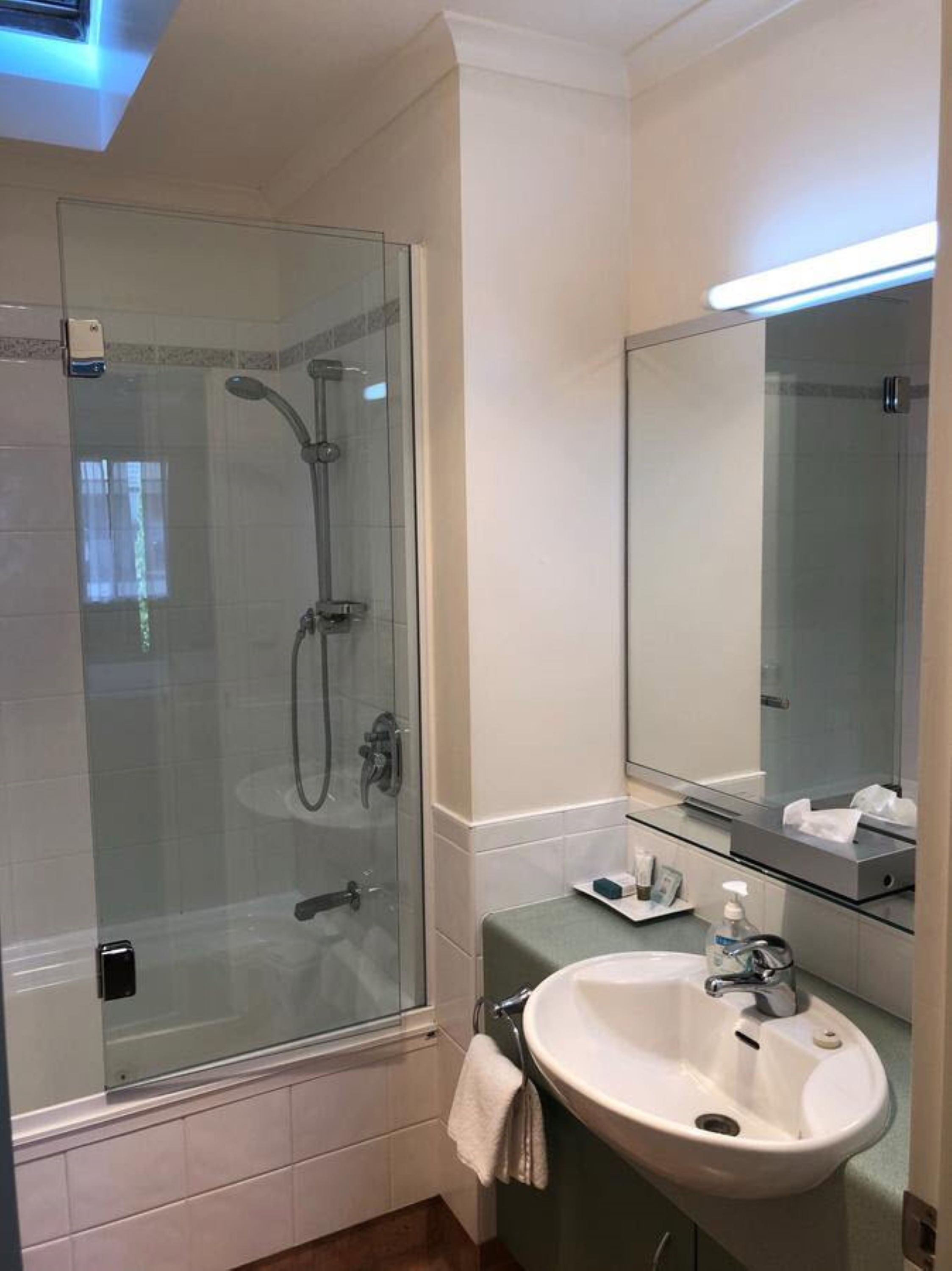 A modern bathroom with a glass-enclosed shower, a white sink, and a mirror above the sink.