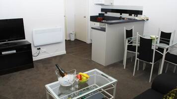 Un espacio habitable compacto con kitchenette, comedor y televisor.