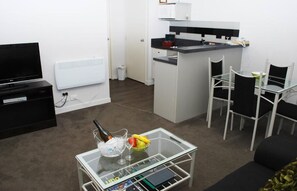 A compact living space with a kitchenette, a dining area, and a TV.
