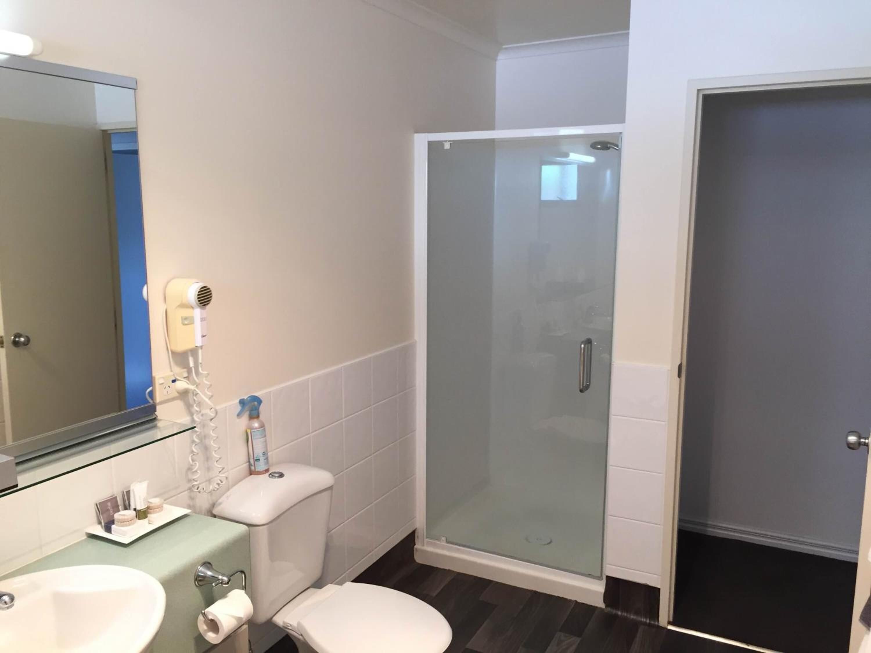 A bathroom with a sink, toilet, and a glass-enclosed shower stall.