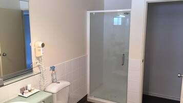 A bathroom with a sink, toilet, and a glass-enclosed shower stall.