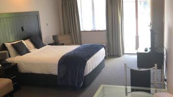 Habitación de hotel con cama, escritorio, silla, ventilador de techo y ventana.