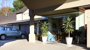 A modern house with a garage, a parked car, and two large potted plants in the driveway. - Bethlehem Motor Inn (Tauranga)