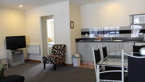 A compact living space with a kitchenette, a dining area, and a seating area. - Bethlehem Motor Inn (Tauranga)