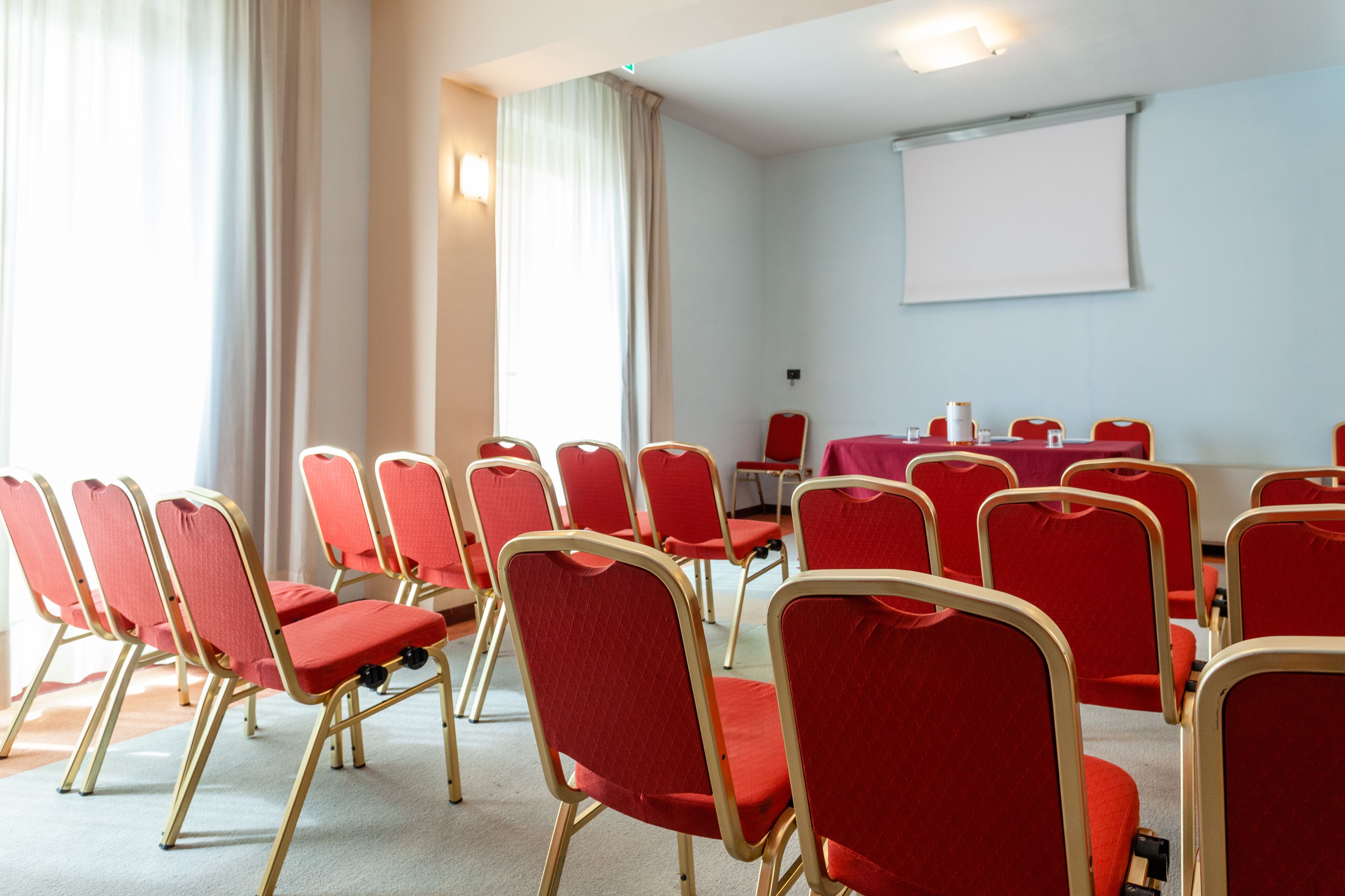 Une salle de conférence avec des chaises rouges et un tableau blanc.