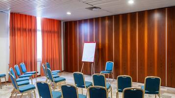 Ett konferensrum med rader av blå stolar, en whiteboard och väggar beklädda med träpaneler.