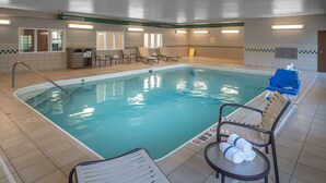 Une piscine avec des chaises longues et une petite table sur laquelle sont posées des serviettes.