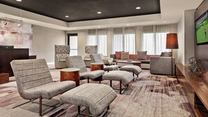 A spacious living area with multiple seating options, including sofas and armchairs, a coffee table, and a television mounted on the wall. - Courtyard by Marriott San Jose South/Morgan Hill (Morgan Hill)