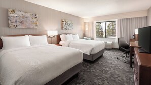A hotel room with two beds, a desk with a flat-screen TV, a chair, and artwork on the walls. - Courtyard by Marriott San Jose South/Morgan Hill (Morgan Hill)