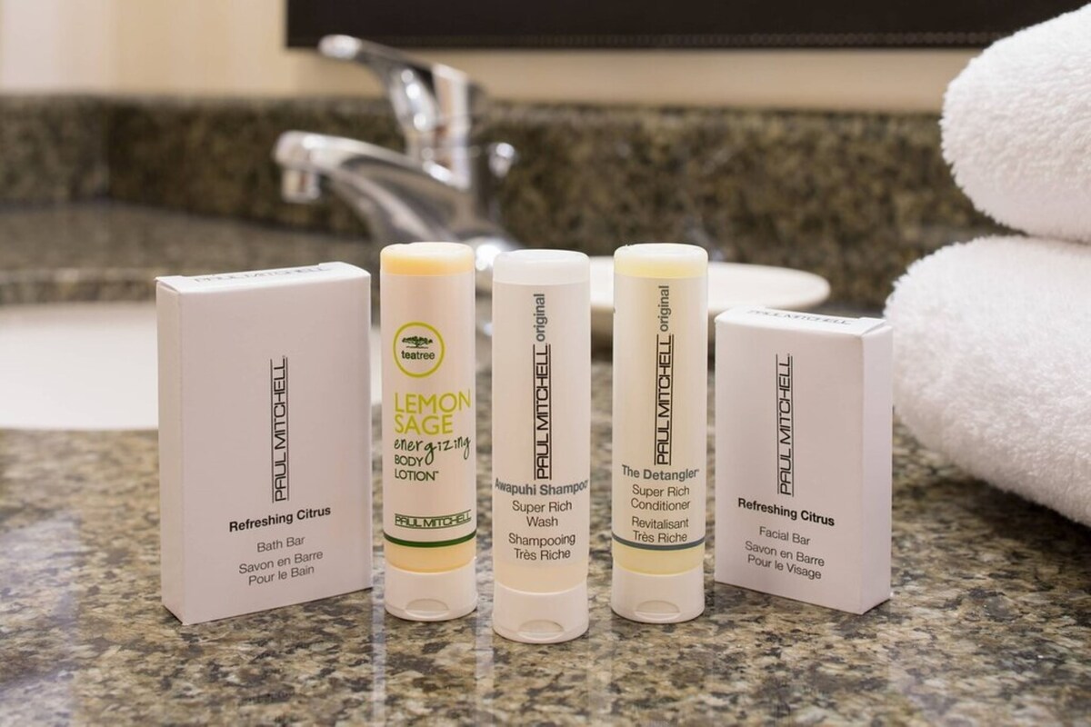 A bathroom counter with various Paul Mitchell products including body lotion, shampoo, conditioner, and facial bar.