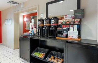 Una estación para desayuno rápido con máquinas de café, dispensadores de agua caliente y alimentos envasados.