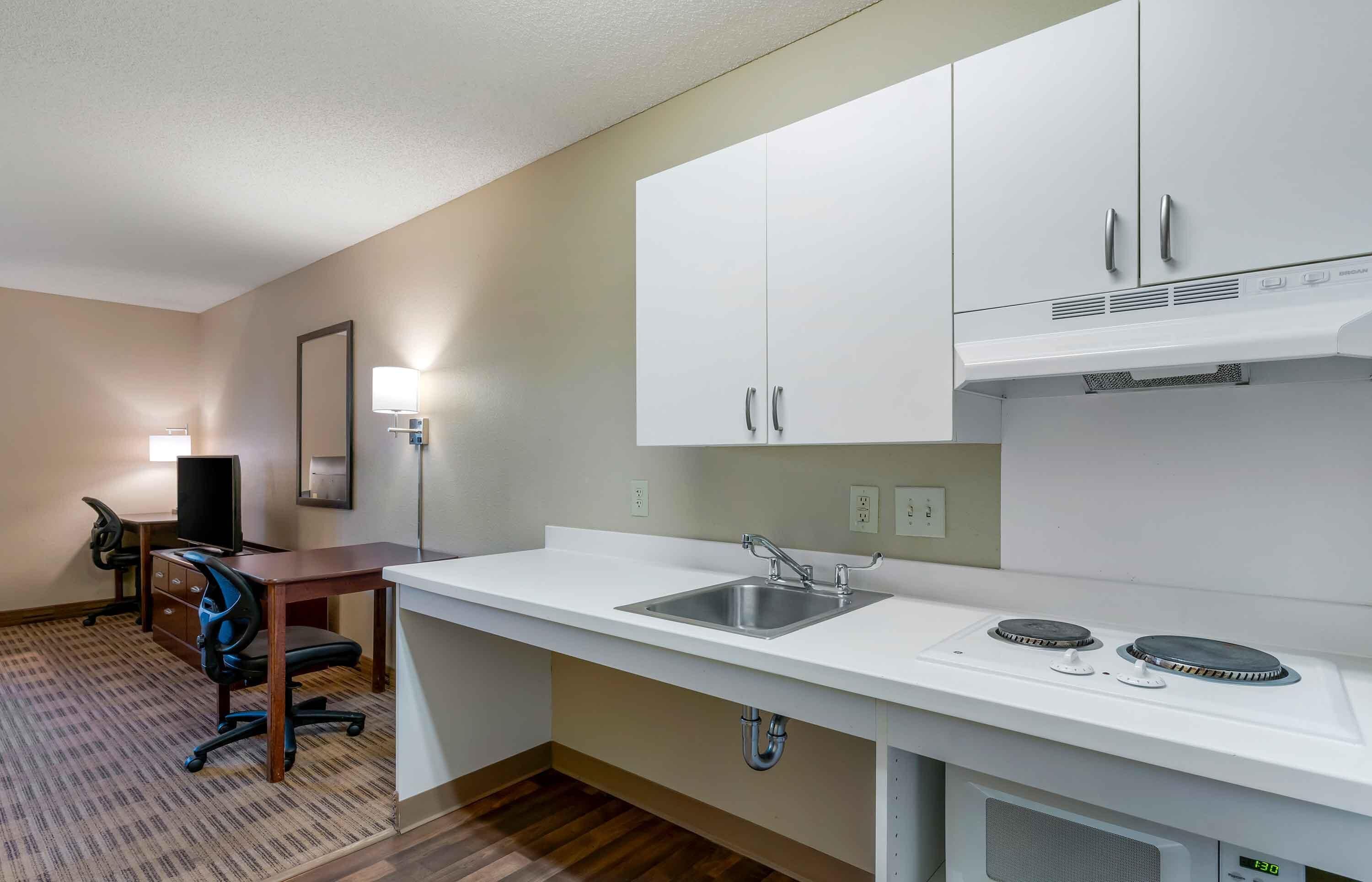 A compact kitchenette with a sink, stove, and cabinets.