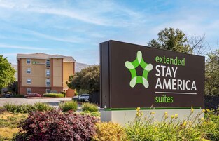 Señal de Stay America con un edificio al fondo.