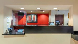 A reception desk with a digital kiosk, a flat-screen TV, and a red accent wall. - Extended Stay America Suites Fremont Warm Springs (Fremont)