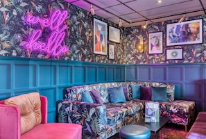 A room with a neon sign, a patterned couch, and framed artwork on the wall. - Premier Inn Manchester Trafford Centre Wst (Manchester)