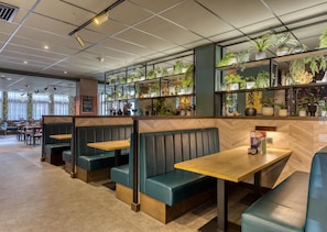 Ein Restaurantinnenraum mit Sitzgelegenheiten, Tischen und Regalen mit Pflanzen.