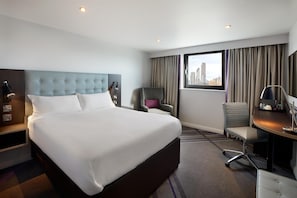 A hotel room with a large bed, a desk, a chair, and a view of the city. - Premier Inn Manchester Trafford Centre Wst (Manchester)