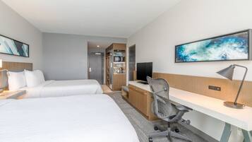 A hotel room with two beds, a desk, a chair, a TV, and a microwave.