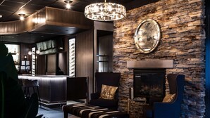 A modern lounge area with a stone wall, a fireplace, and a bar counter. - Hilton Garden Inn Pittsburgh/Southpointe (Canonsburg)