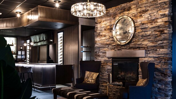 Un espace de détente moderne avec un mur en pierre, une cheminée et un comptoir de bar.