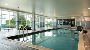 Une piscine intérieure avec des parois en verre transparent, un sol carrelé et un poste de surveillance pour le sauveteur.