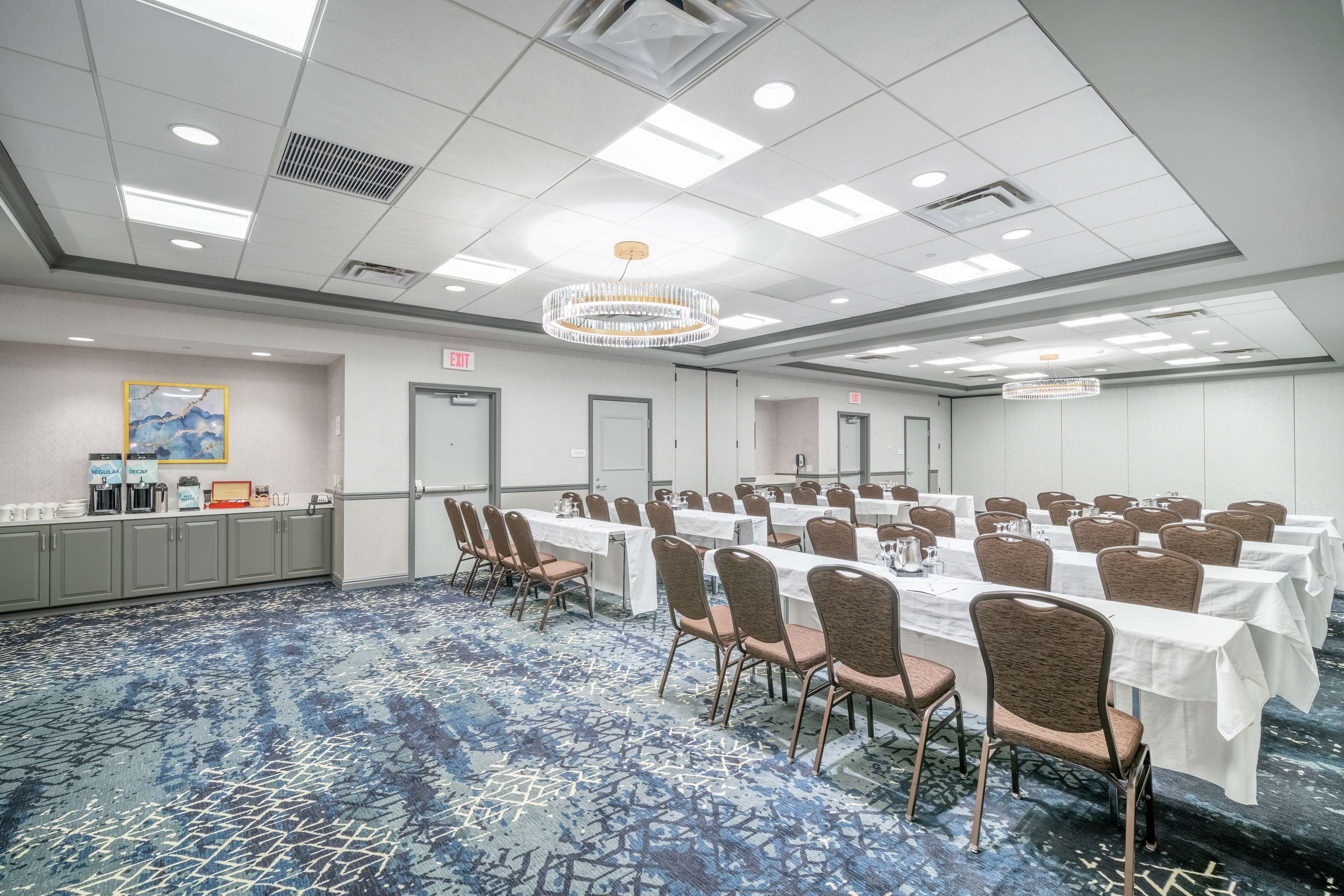 A conference room with tables and chairs, a chandelier, and a patterned carpet.