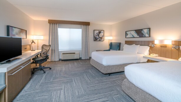 A hotel room with a bed, a desk with a TV, a chair, a lamp, and a window with curtains. - Hilton Garden Inn Pittsburgh/Southpointe (Canonsburg)