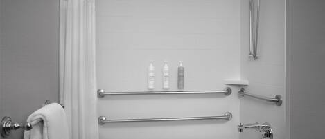 Ein modernes Badezimmer mit Badewanne, Haltegriffen und Duschkopf.