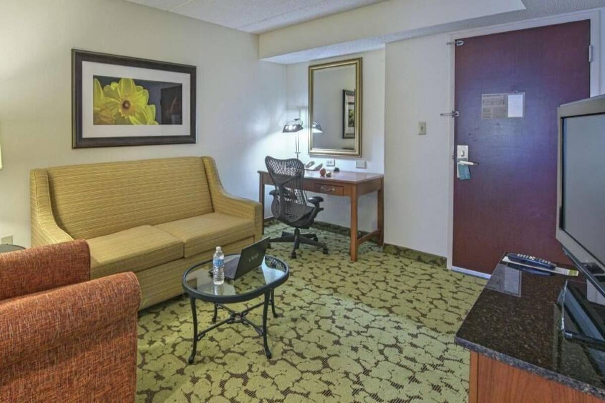 Une chambre d’hôtel équipée d’un canapé, d’un fauteuil, d’un bureau, d’une chaise et d’un téléviseur.