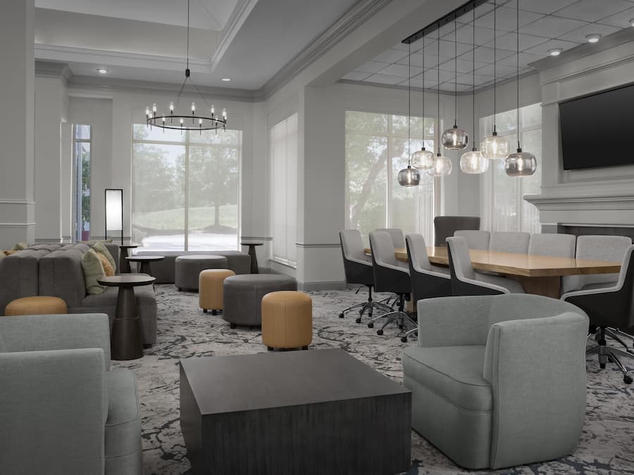 A modern conference room with grey and beige furniture, large windows, and a flat-screen TV.